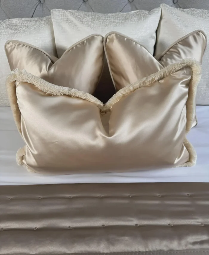luxury satin cushion cover with ecru fringe layed nicely on a bed
